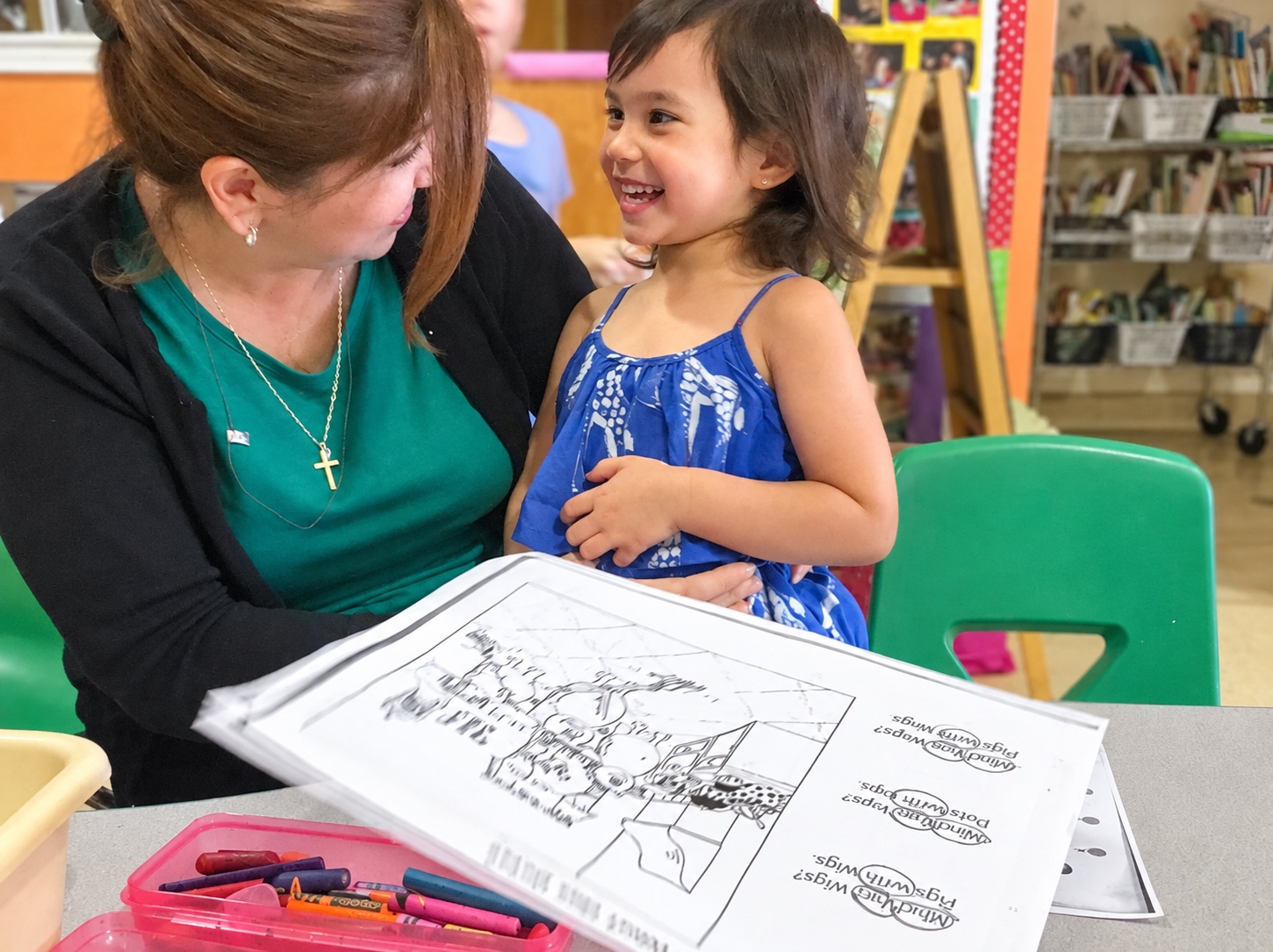 A smiling child sharing a learning moment with a teacher at Kinder Casa