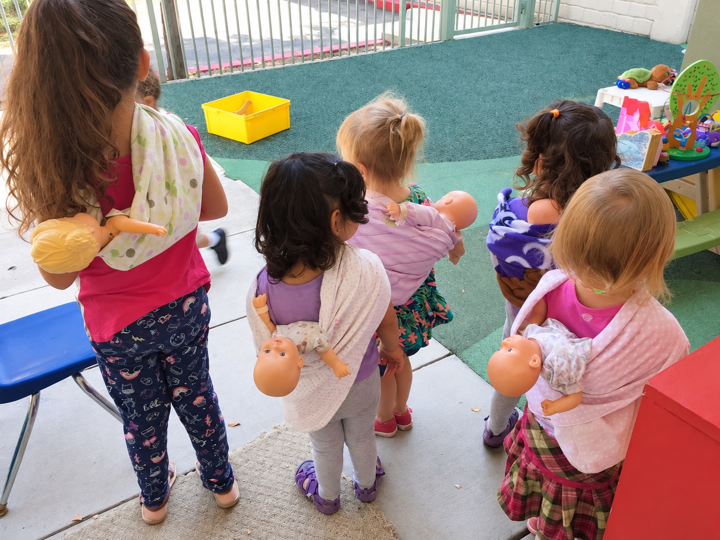Children exploring pretend play with dolls at Kinder Casa